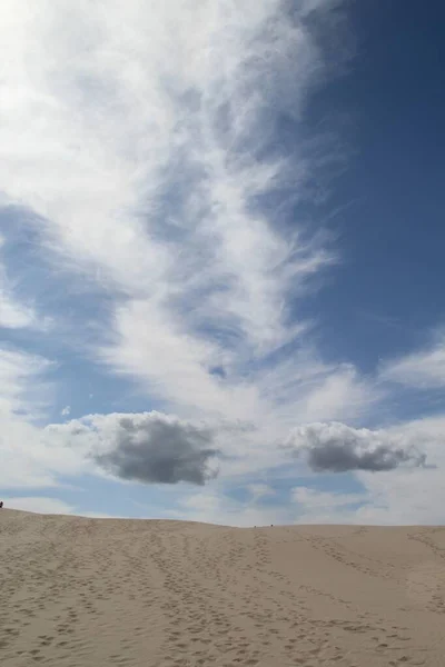 Vertikal bild av en sandig kulle med fotspår under en blå molnig himmel — Stockfoto