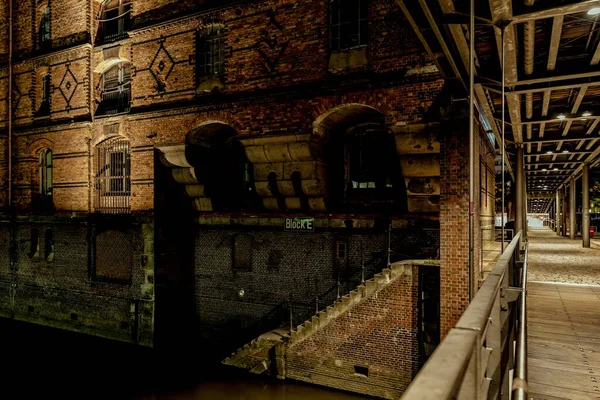 Plan nocturne d'un vieux bâtiment en brique près d'un pont souterrain éclairé par des lampadaires — Photo