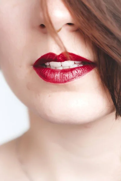 Gros plan vertical d'une femelle portant du rouge à lèvres rouge avec un léger sourire — Photo