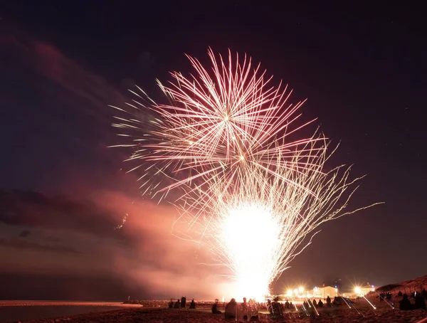 Beautiful horizontal shot of fireworks at night time with people celebrating under the colorful sky — Stock Photo, Image