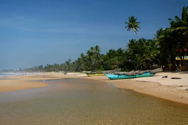 Pukulan yang lebar dari pantai yang indah dengan perahu dan pohon palem pada hari yang cerah — Stok Foto