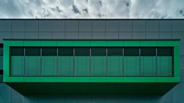 Tiro horizontal de um belo edifício cinzento e verde sob o deslumbrante céu nublado — Fotografia de Stock