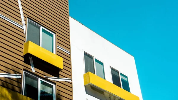 Disparo de ángulo bajo de edificios modernos de hormigón marrón y blanco con balcones amarillos — Foto de Stock