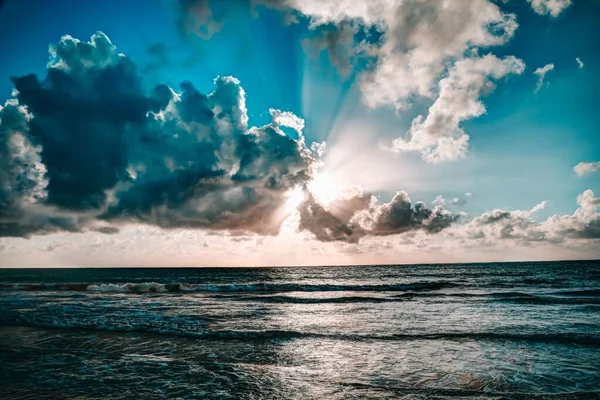 美丽的阳光躲在令人叹为观止的云彩后面 把它的光芒洒向大海 — 图库照片
