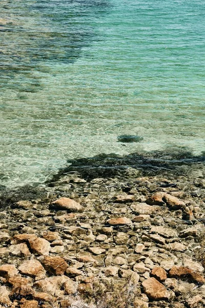 白天在岩石附近的清澈海水的垂直拍摄 — 图库照片