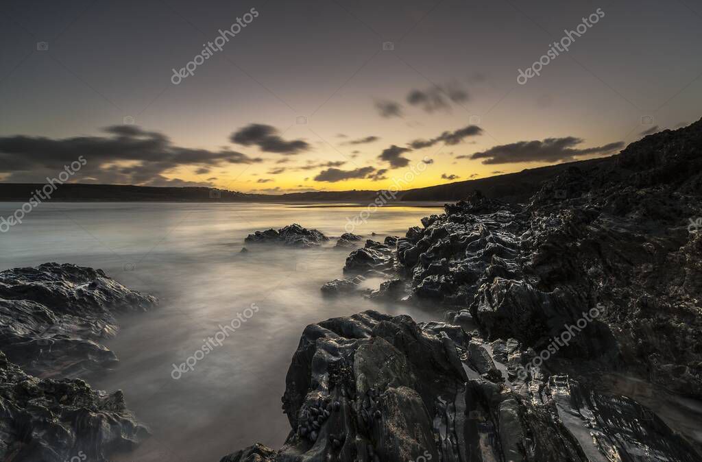 A horizontal shot of water splashing to the mountains during sunset in Cornwall, UK
