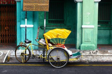 Horizontal shot of a yellow cycle rickshaw in Georgetown, Malaysia clipart