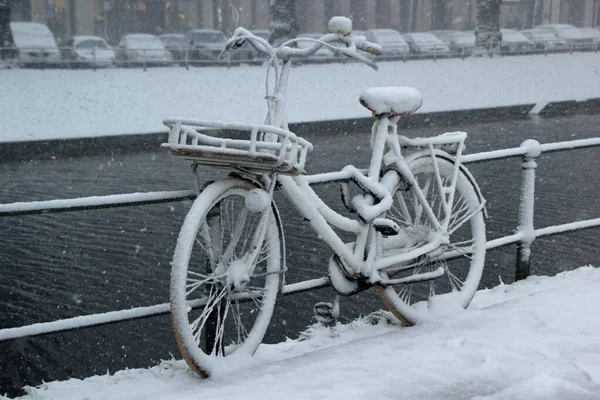 Fiets leunde tegen een hek in de buurt van het water bedekt met sneeuw — Stockfoto