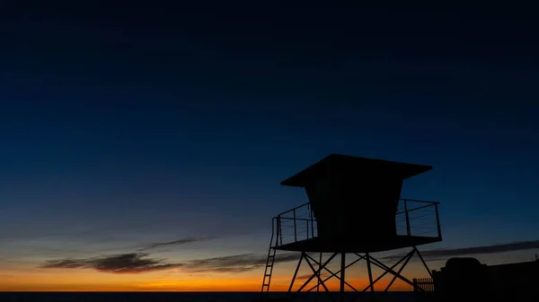 Horizontal shot of a beach watchtower in silhouette during golden hour sunset — Stock Photo, Image