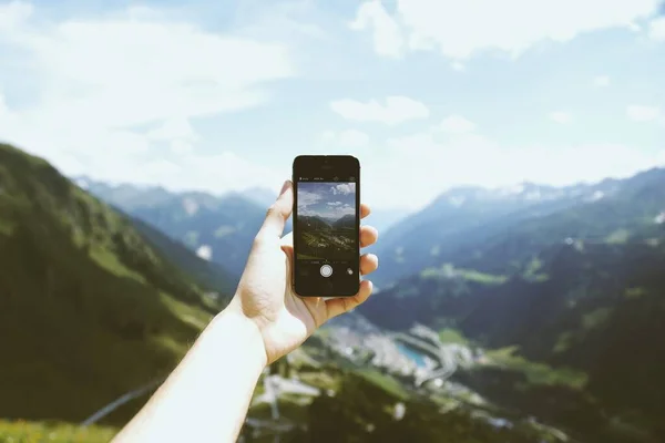 Persona con un teléfono inteligente que toma una foto de los hermosos alrededores, ideal para un fondo fresco — Foto de Stock