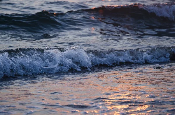 Гарний Знімок Водойми Хвилями Розбризкують Пляж Під Час Заходу Сонця — стокове фото