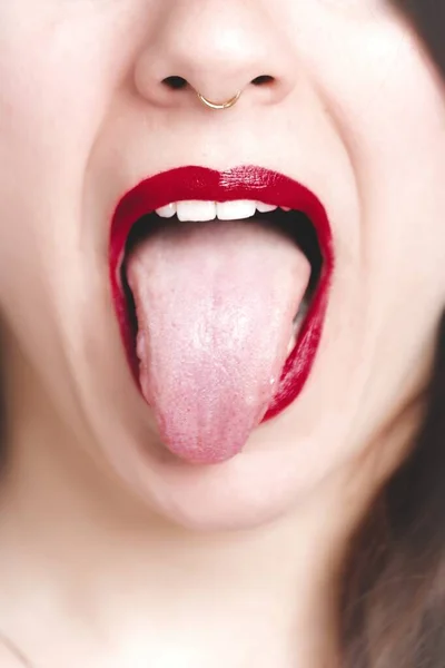 Primer plano vertical de una hembra con lápiz labial rojo mostrando su lengua — Foto de Stock