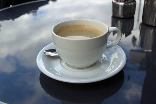 Zamknij ujęcie kawy na szklanym stole z zamazanym tłem — Zdjęcie stockowe