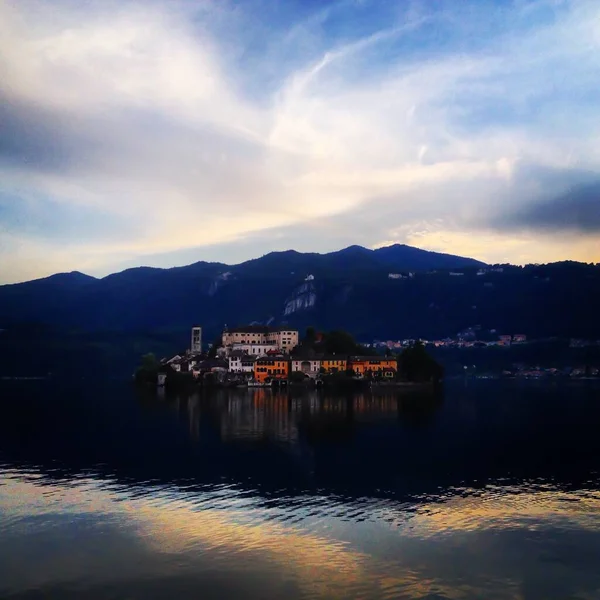 Beautiful scenery of apartment buildings near the body of water surrounded by high rocky mountains — Stock Photo, Image