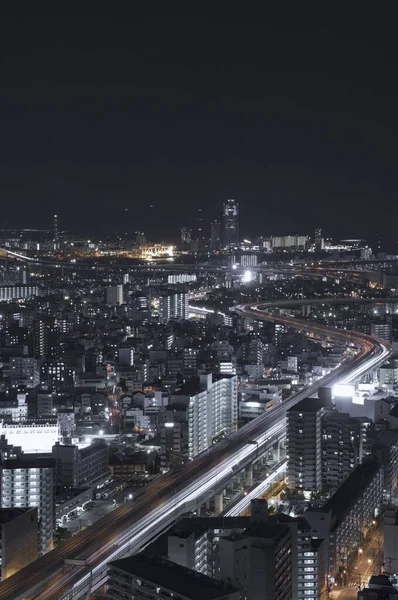 城市建筑物和夜间行驶在路上的车辆的垂直时差照片 — 图库照片