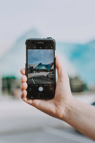 Eine Person mit schwarzem Telefon fotografiert ein dreieckiges architektonisches Gebäude — Stockfoto