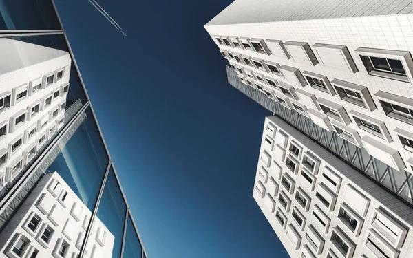 Imagen de bajo ángulo de un moderno edificio blanco con ventanas rectangulares con un avión en el cielo — Foto de Stock