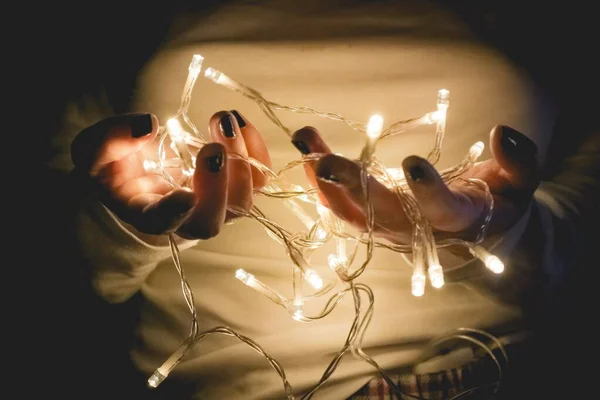 Gros plan d'une personne portant une chemise blanche à manches longues tenant allumée des lumières à ficelle — Photo