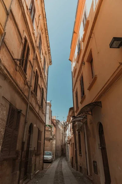 Vertical shot of a narrow alleyway in the middle of buildings under a blue sky at daytime — Φωτογραφία Αρχείου