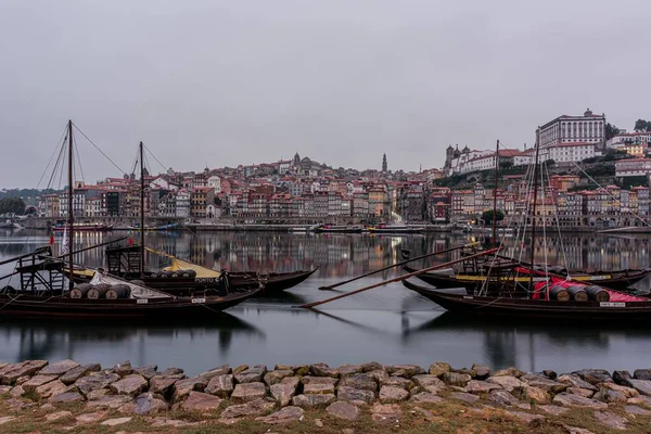 Hermosa toma de barcos en el agua con la construcción en la distancia y un cielo nublado en el fondo — Foto de Stock