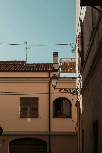 Vertical shot of buildings with a lamp post attached to a wall and a blue sky in the background — 图库照片