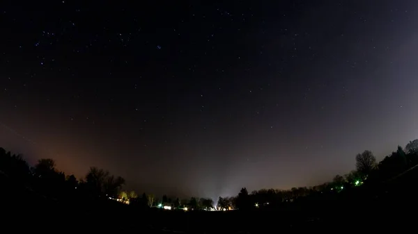 Ojo de pez tiro de luces de la ciudad en la distancia bajo el hermoso cielo nocturno estrellado —  Fotos de Stock