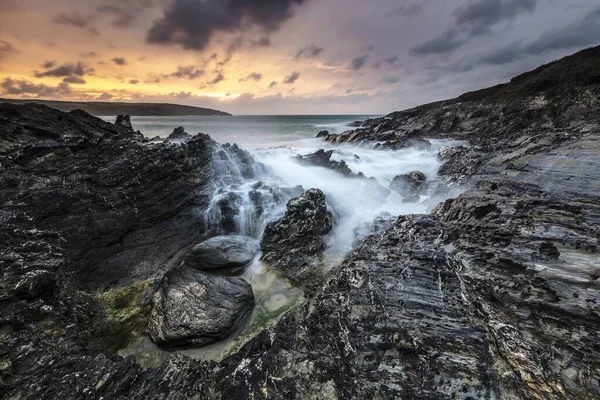 Lanzamiento horizontal de agua salpicando a las montañas durante el atardecer en Cornwall, Reino Unido — Foto de Stock