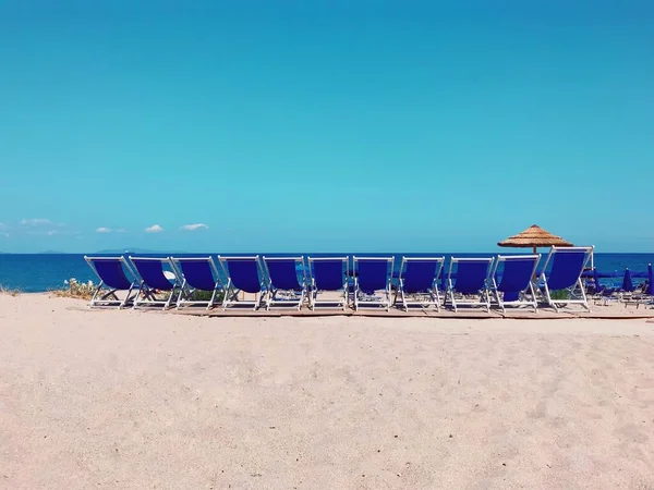 Plan horizontal de parasols bleus sur la plage sous le ciel clair par une journée ensoleillée — Photo