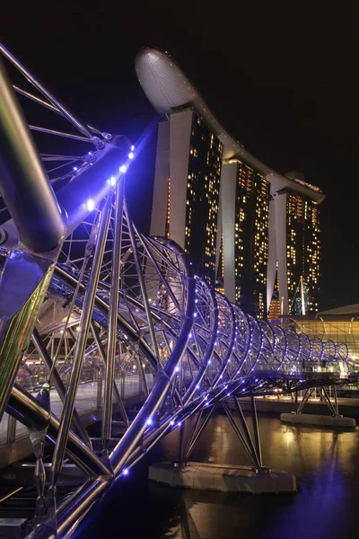 Вертикальний знімок моста Гелікс у Сінгапурі з сучасним хмарочосом на задньому плані. — стокове фото