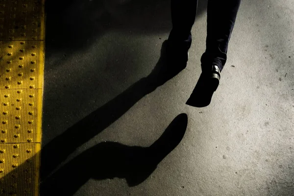 Poziome ujęcie cienia mężczyzny chodzącego nocą po ulicy — Zdjęcie stockowe