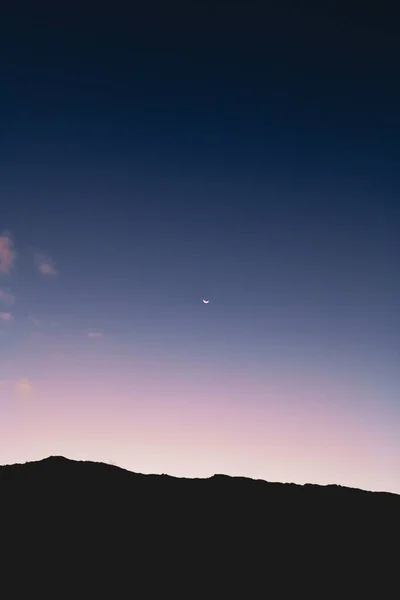 Low angle shot of the moon in the colorful night sky