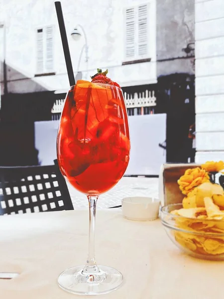 Vertikale Aufnahme eines roten alkoholischen Getränks in einem Champagnerglas mit Erdbeeren an der Spitze — Stockfoto