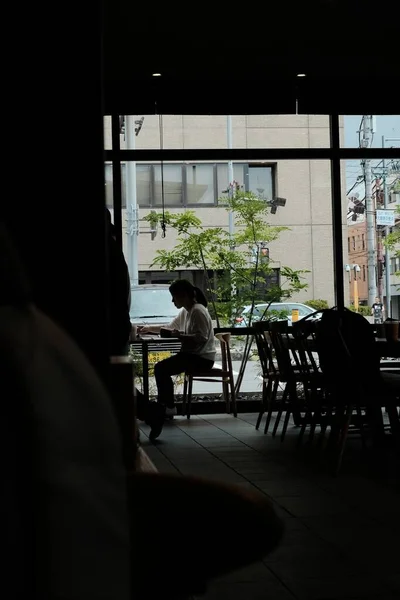 Plan vertical d'une jeune femme solitaire assise dans un café attendant son café du matin — Photo