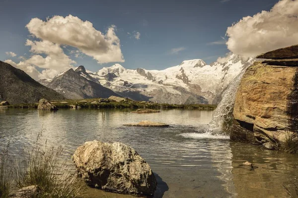 Paisagem de tirar o fôlego de um lago e uma cachoeira ao lado em Saas-Grund, Suíça — Fotografia de Stock