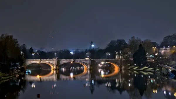 Horizontale Aufnahme einer Betonbrücke, die sich wunderschön im See unter dem Nachthimmel in turin, Italien widerspiegelt — Stockfoto