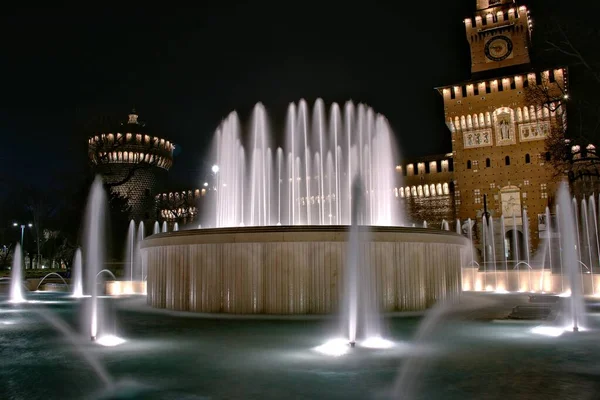 Foto orizzontale di fontane con luci di fronte a un edificio italiano di notte a Milano — Foto Stock