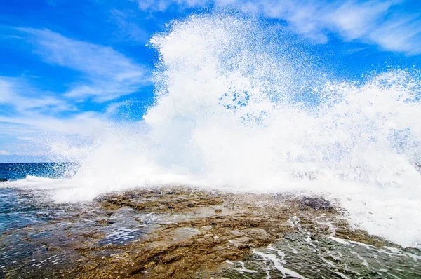 Silný šplouchání vody stoupající ze středu oceánu a vrhající se na skálu — Stock fotografie