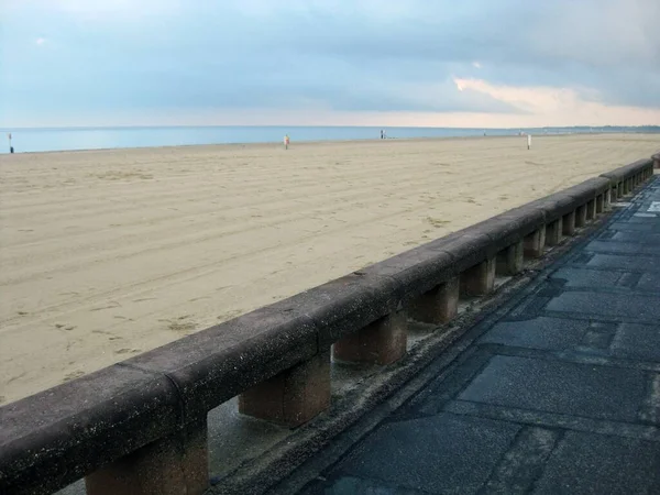 Belo tiro de uma costa oceânica com pessoas caminhando sob o céu limpo — Fotografia de Stock