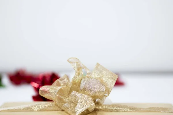 Closeup shot of a golden ribbon with a bow and a blurred background — Stock Photo, Image