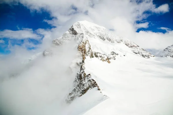 Bel colpo di montagne innevate con un cielo nuvoloso blu sullo sfondo — Foto Stock