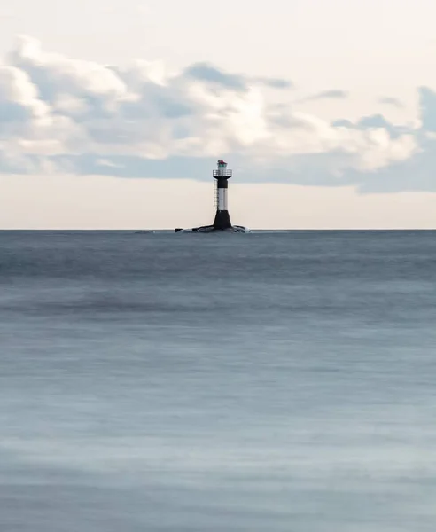 Vue verticale de la mer avec un phare au loin et un ciel nuageux blanc en arrière-plan — Photo