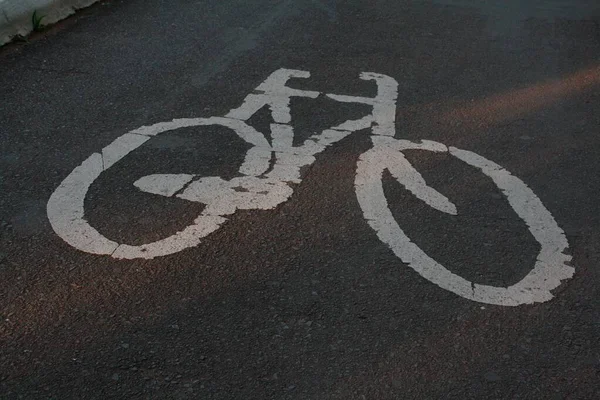Высокоугольный снимок белого велосипедного знака, нарисованного на асфальтовой дороге. Идеально подходит для использования дорожных знаков . — стоковое фото