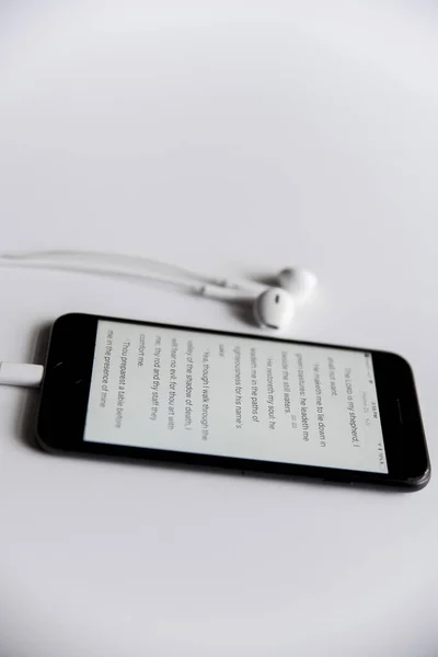 Vertikale Aufnahme der Bibel auf einem Smartphone auf einer weißen Oberfläche — Stockfoto
