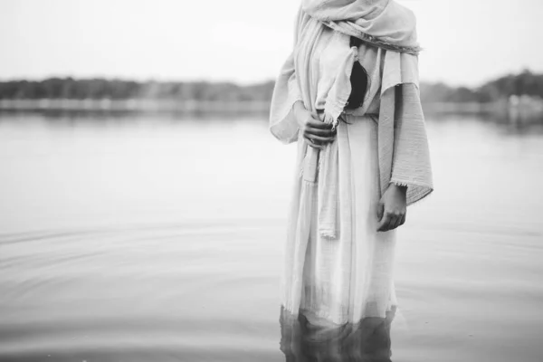 Female wearing a biblical robe while standing in the water in black and white