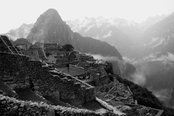 Escala gris de un pueblo en una montaña brumosa —  Fotos de Stock