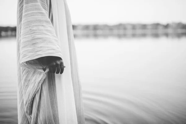 Közelkép egy személyről, aki bibliai köntöst visel, miközben a vízben áll fekete-fehérben. — Stock Fotó