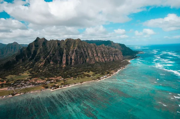 Vue en angle élevé d'une île avec des montagnes boisées sous un ciel nuageux — Photo