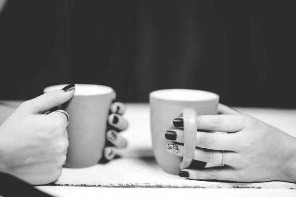 Nahaufnahme von Frauen, die ihren Kaffee schwarz-weiß auf dem Tisch halten — Stockfoto