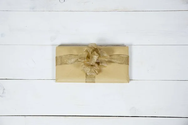 Накладний знімок подарунка з золотою стрічкою на білій дерев'яній поверхні — стокове фото