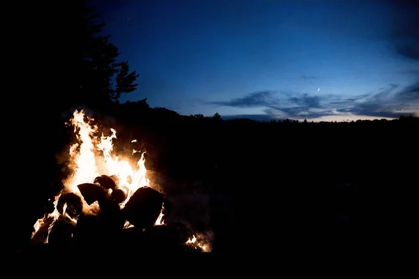 Beautiful shot of the campfire with a dark blue sky in the background at night time — Stock Photo, Image